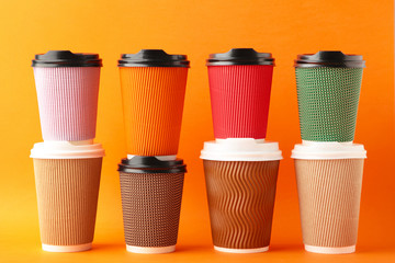 Many different cups of coffee on orange background. Top view