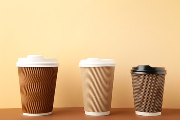 Three brown cups of coffee on beige background. Top view