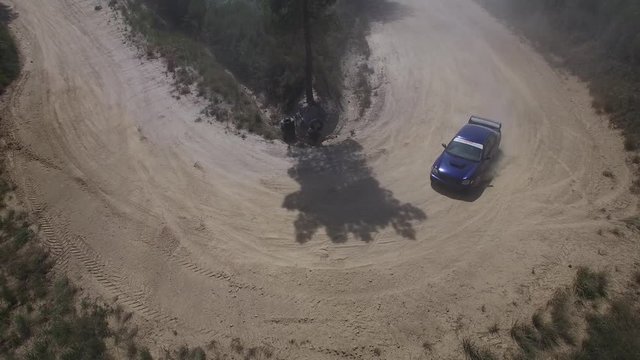 Aerial of subaru wrx sti rally car driving around a hairpin turn slowly