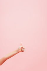 partial view of kid showing thumb up isolated on pink with copy space