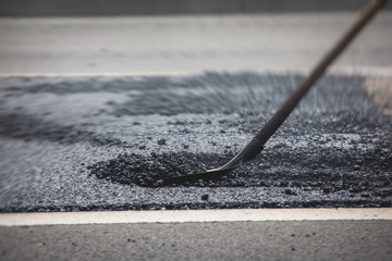 Asphalt paver machine and steam road roller during road construction and repairing works, process of asphalting and paving, workers working on the new road construction site, placing a layer