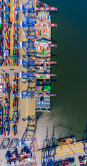 Container ship in export and import business and logistics. Shipping cargo to harbor by crane. Water transport International. Aerial view