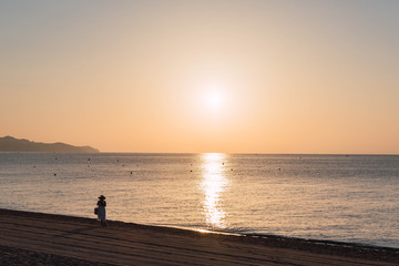 Naklejka na ściany i meble Woman on the beach during sunrise