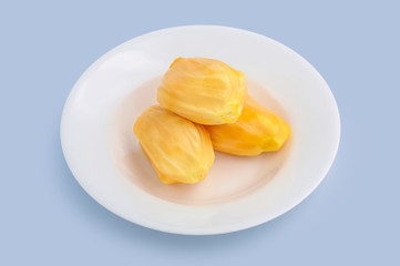 Fresh yellow tropical jackfruit on white dish isolated on light blue background, clipping path included.