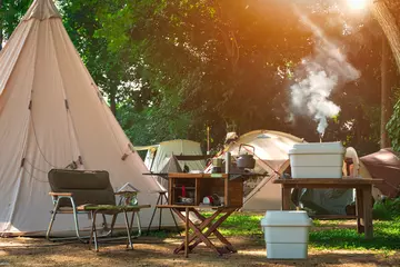 Crédence de cuisine en verre imprimé Camping Équipement de cuisine extérieure et ensemble de table en bois avec groupe de tentes de terrain dans une zone de camping dans un parc naturel