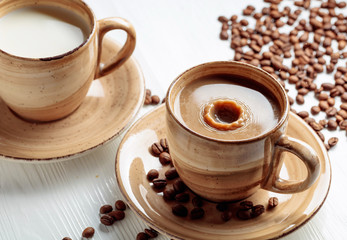 Latte and coffee beans on a white wooden table.