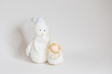 Snowman toy and christmas angel on light gray background 