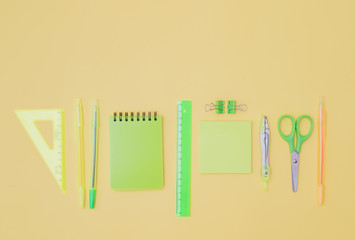 Flat lay border with school supplies on a yellow background