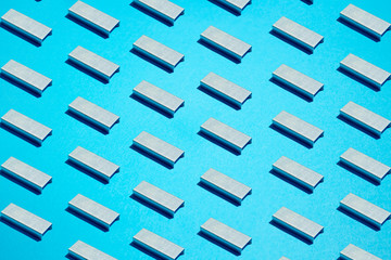 Back to school pattern made of staples. Isometric stack of metal staples for stapler on blue background - obrazy, fototapety, plakaty