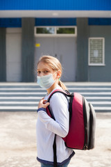 Primary school girl going to school in   medical mask