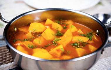 Potato and tomato curry in a steel bowl.