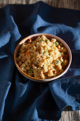 South Indian breakfast vegan savory vegetable semolina porridge Rava Upma on blue textile background. Authentic vegetarian food still life.
