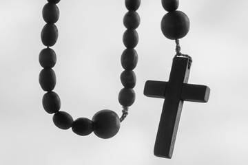 Close up rosary beads against white background. Selactive focus on cross. Christianity, religion, faith concept.