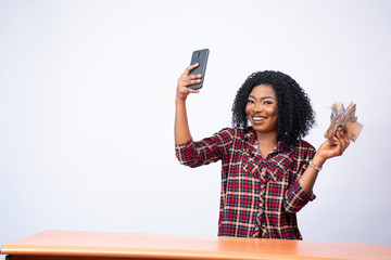 beautiful black lady taking a selfie with a wad of cash - obrazy, fototapety, plakaty
