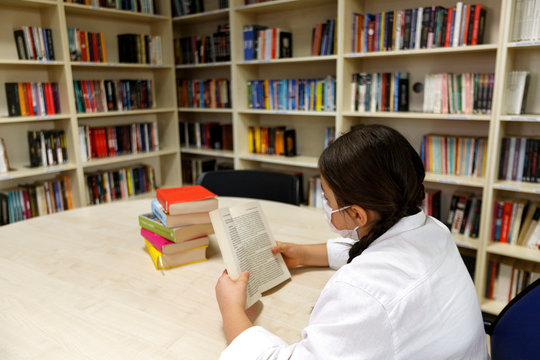 Student Working In The Library With A Face Mask. 