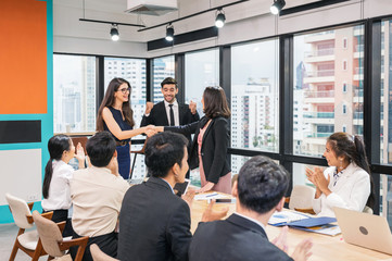 Multi ethnic businesswoman shaking hands cooperation for corporate agreement with coworkers in office