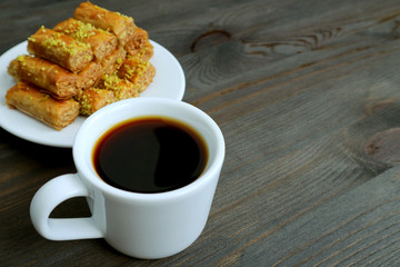 Cup of Turkish Coffee on Wooden Table with Blurry Pistachio Nuts Baklava Pastries in the Backdrop