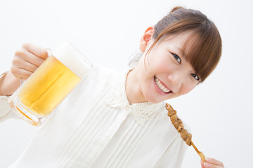 焼き鳥とビールを飲む女性