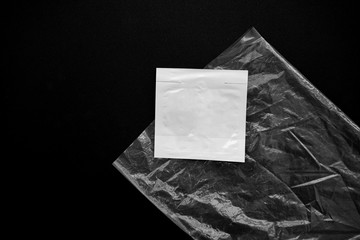 Grungy blank paper against plastic wrapper on black background overlay texture