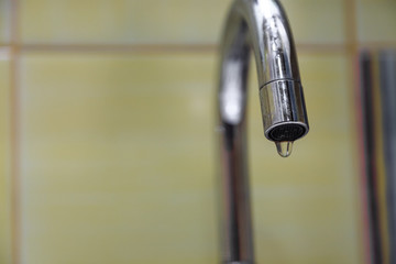 The crane is leaking. a drop of water drains from the tap. leaking plumbing.