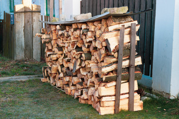 Woodpile with fresh wood at a private house on the street. Preparing for the cold winter in the village.
