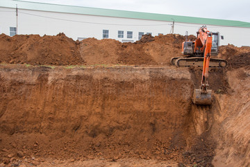 The construction site excavator digs a deep pit. Digger. Construction machinery. Excavation at a construction site