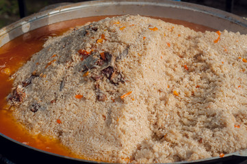 Cooking Uzbek pilaf. National food. Roasting meat in a large cauldron. Large pot with Uzbek pilaf