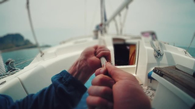 Man on the boat POV. Man holds the rope on the sailing boat