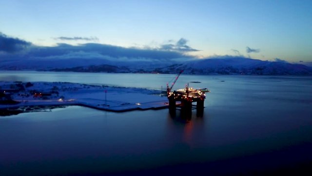 Aerial of arctic oil drilling platform rig during polar night sunset