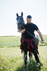 Arab tall beard man wear in black with arabian horse.