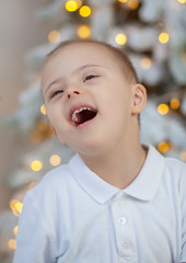 A little boy with Down syndrome at the New Year's tree, a child with a genetic disorder, children...