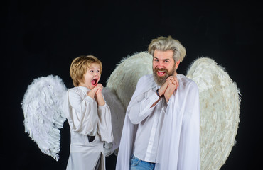 Obraz premium Father and son Angels. Valentines angels. Happy father with little son in angel costumes. Valentines day. Cute angel. Little cupid boy gives father gift. Halloween angels.