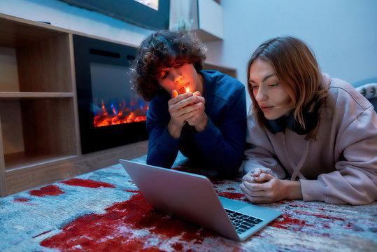 Enjoying Weed At Home. Young Teenage Couple Smoking Marijuana And Using Laptop While Lying On The Floor In The Living Room. Guy Lighting Cannabis Weed Cigarette