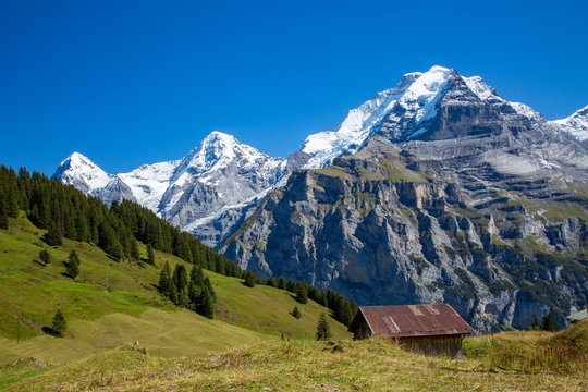 A typical alpine chalet along the Eiger trail. Eiger, Monch and Jungfrau mountains are in the background.