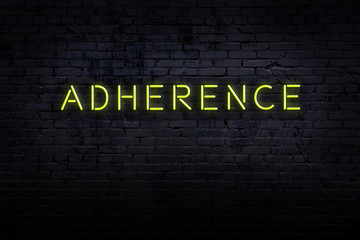 Night view of neon sign on brick wall with inscription adherence