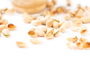 Peeled pistachios in mortar on a white background