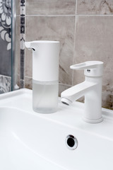 Close up on a Modern automatic soap dispenser in hommy bathroom on a sink