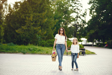 Obraz premium Family in a summer park. Mother in a blue pants. Basket with fruits.