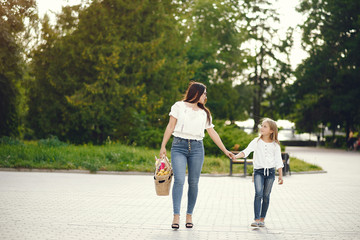 Fototapeta premium Family in a summer park. Mother in a blue pants. Basket with fruits.