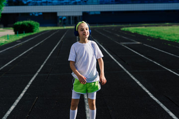 Girl jogging on a sunny summer evening, laying on treadmill, stadium, physical training, back to...