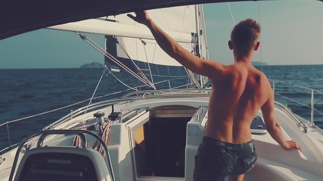 Man sailing. Young man sailing in the tropics and looks at the sails