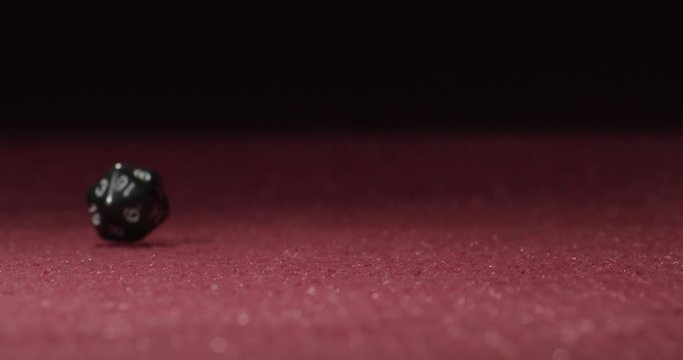Close-up of Black 20-Sided Dice Rolling in Slow Motion Revealing 10 Side