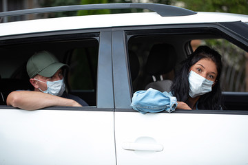 Woman and her husband in the background wearing a protective mask. Car couple. Mask. COVID-19.