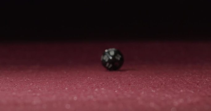 Close-up of Black 20-Sided Dice Rolling in Slow Motion Revealing 17 Side