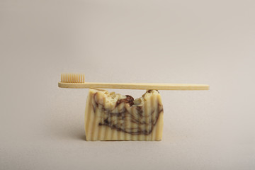 A bamboo toothbrush and a set of handmade soap on the beige background. Natural hygiene products. Zero waste concept.