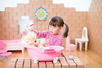 young girl pretend play babysitting with baby doll at home