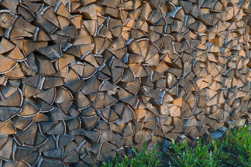 A woodpile of dry birch wood in the backyard of the house close-up.
