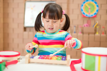 young girl play xylophone at home for homeschooling
