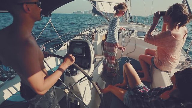 Friends sailing. Four friends sailing in the tropics, man steers and women relax