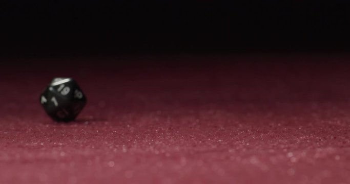 Close-up of Black 20-Sided Dice Rolling in Slow Motion Revealing 20 Side